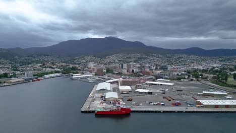 Pequeño-Barco-Rojo-Tasmania-Hobart-Muelles-Helicóptero-Pas-Montaña-Nublado-Alto-Drone-50fps