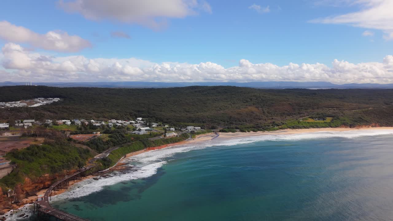 Wide ocean establishing of Catherine Hill Bay beach and clear blue sea horizon in New South Wales, aerial pullback of coastline
