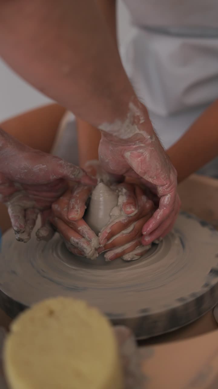 Hands molding clay on a pottery wheel