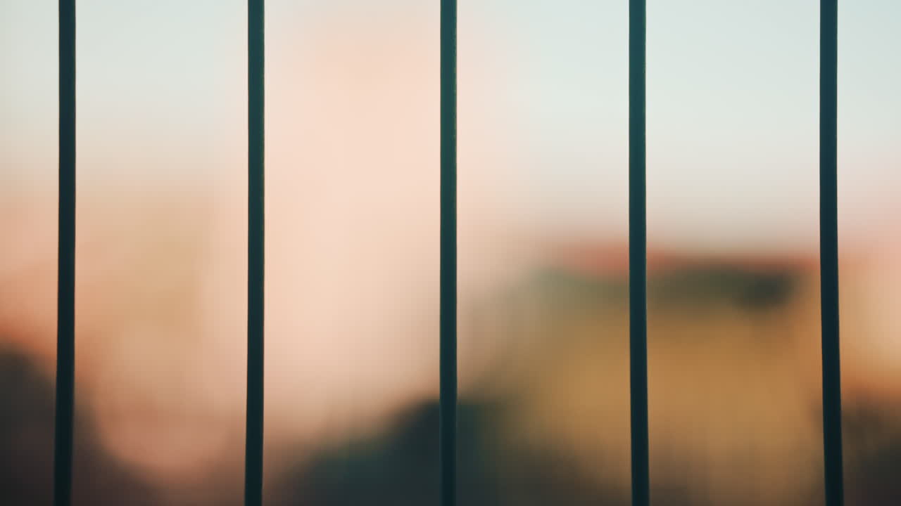 Close up shot of vertical metal fence bars with blurred colorful background