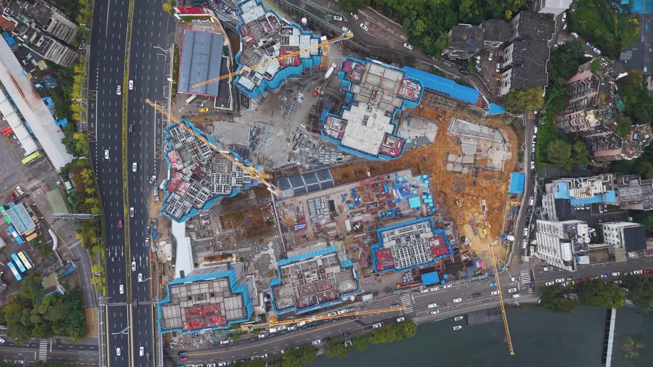 Top-down aerial of a high-density construction site in Guiyang, Guizhou Province, China. Highlights multiple cranes, foundation work, and surrounding urban infrastructure