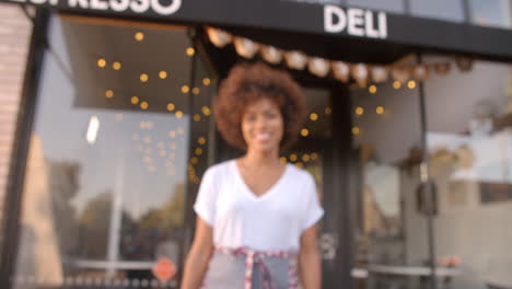 black female owner walks into focal plane in front of cafe