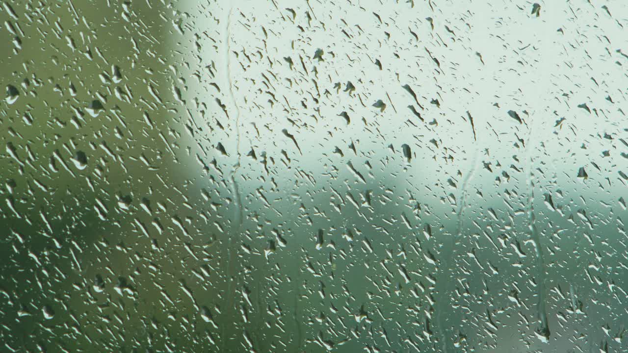 gotas de lluvia deslizándose lentamente sobre el cristal de la ventana en un día lluvioso, toma de primer plano medio