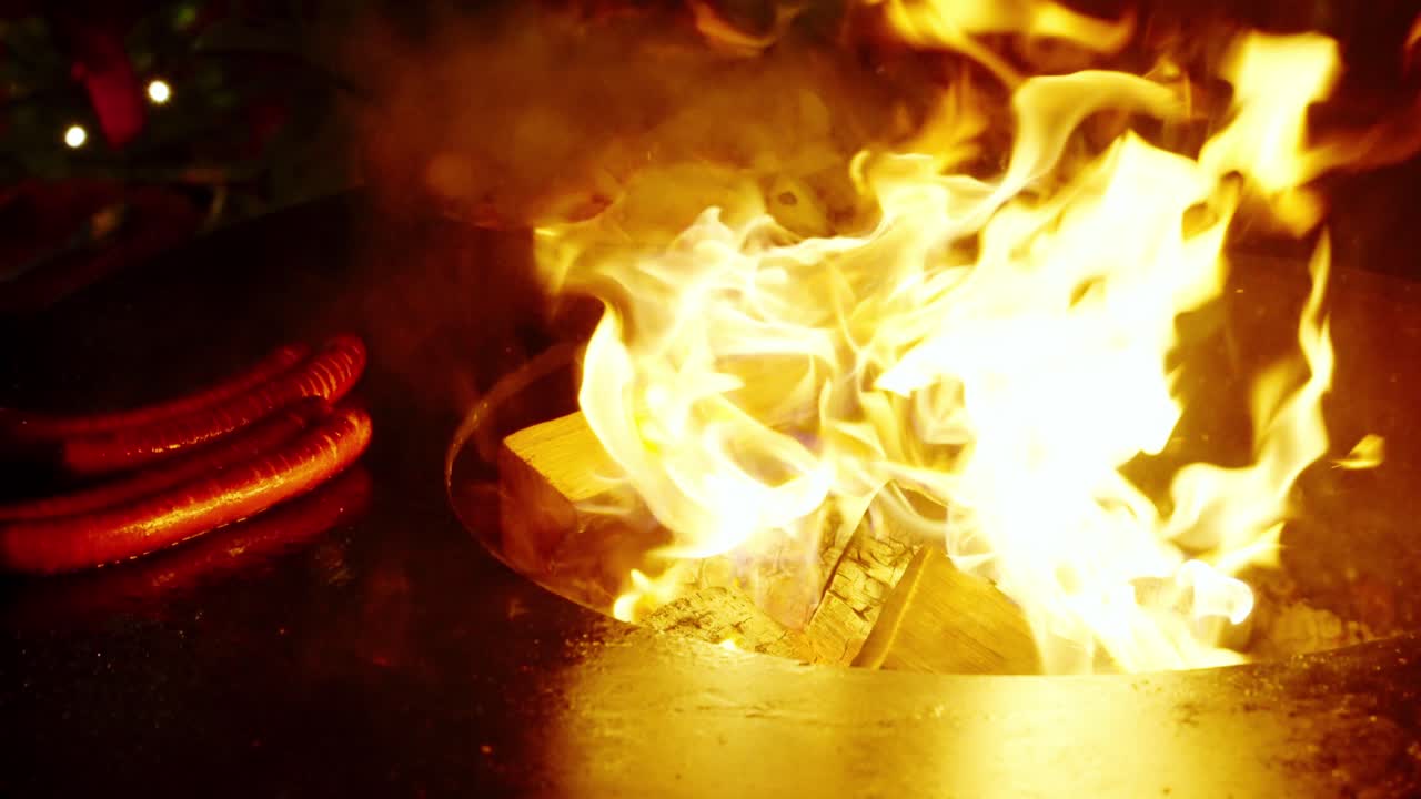 salchichas a la parrilla sobre llamas abiertas en un mercado navideño festivo en un entorno nocturno cálido y acogedor