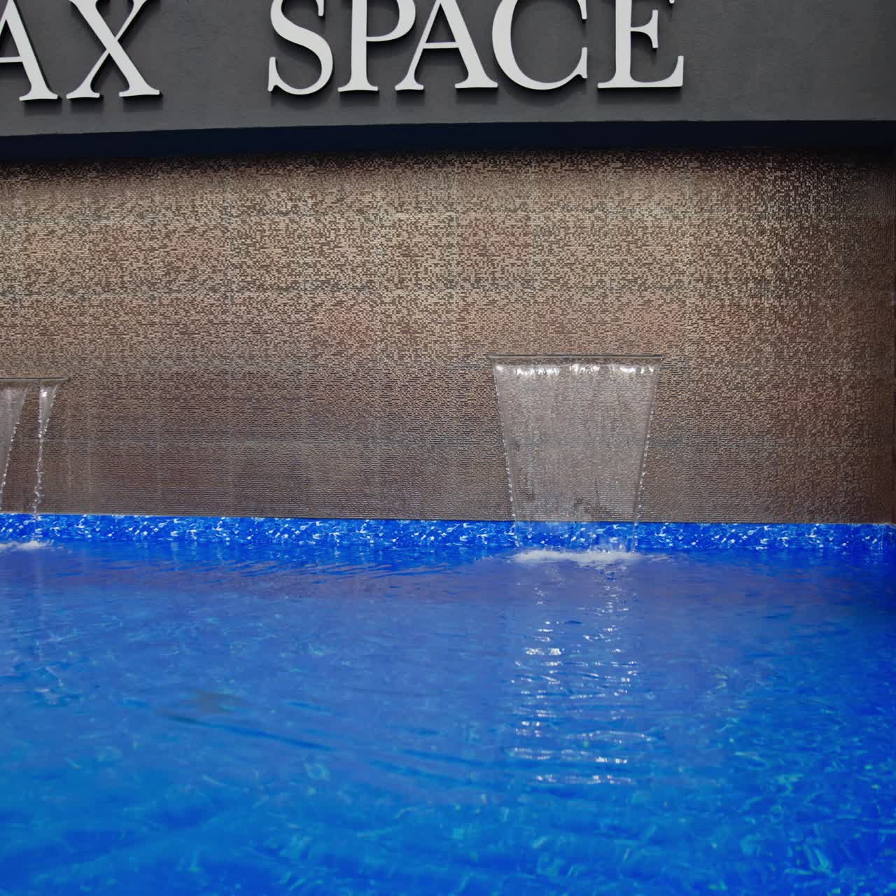 Happy smiling models wearing swimsuits and white shirts sitting at the little pool outdoors. Ladies posing smiling touching hair