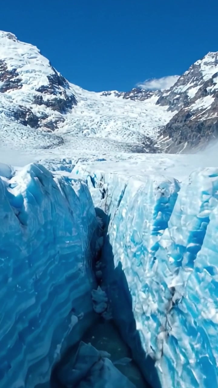 Maestoso paesaggio glaciale con profonde fessure e strutture di ghiaccio glaciale sotto un cielo azzurro limpido, evidenziando l'incredibile bellezza della natura e le formazioni geologiche
