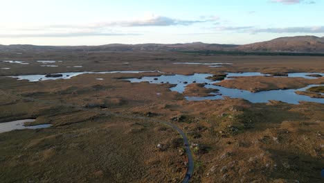 Amplia-Toma-De-Drones-De-Los-Lagos-De-Connemara-Con-Carreteras-Y-Pequeños-Lagos-Tranquilos-En-Primer-Plano-Y-La-Cordillera-De-Beanna-Beola-En-La-Distancia,-Toma-Aérea-Lenta-Y-Reveladora