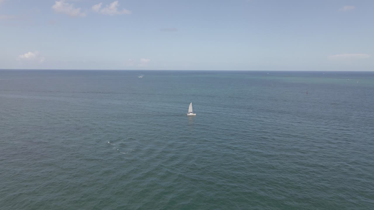 la antena oceánica se centra en el velero catamarán en el atlántico verde y plano.