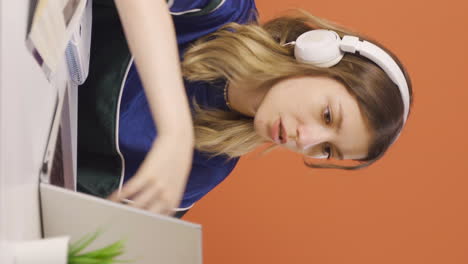 video vertical de una mujer joven cerrando una computadora portátil con una expresión de enojo.