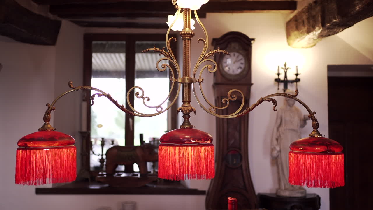 candelabro vintage con pantallas de lámparas de borde rojo en una habitación llena de antigüedades