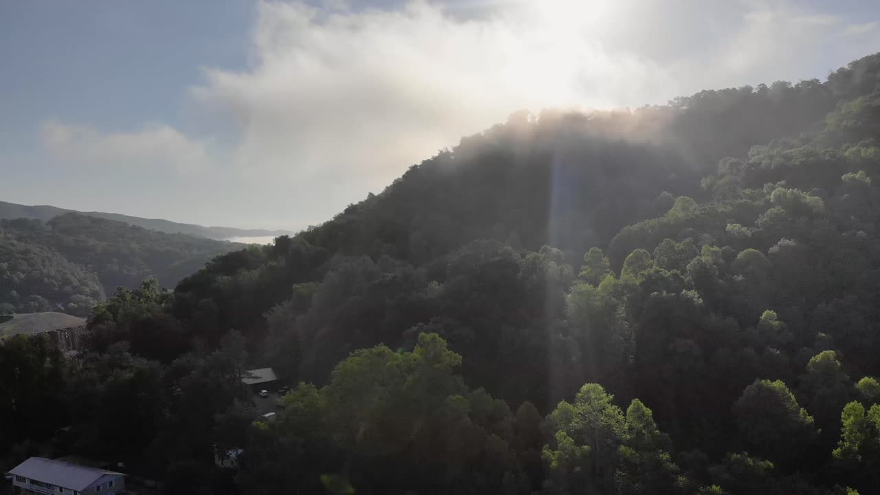 Beautiful Sun Flare Peaking Over a Lush Green Mountain Drone Shot fps 30 at 4k