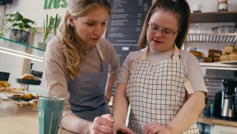 chica con síndrome de down navegando por teléfono junto con su compañero de trabajo en el café
