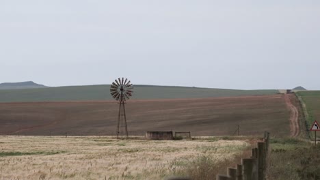 molino de viento y bomba de agua en un campo de trigo