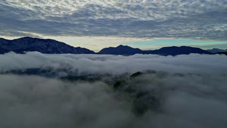 mountain peeks above cloudscape, aerial drone view