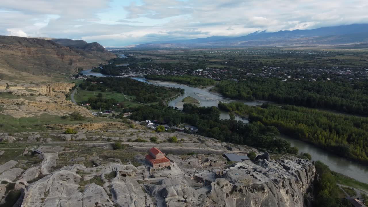 Aerial wide of Uplistsikhe cave city on rocky cliffs surrounded by mountain