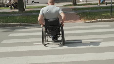 man with disabilities in wheelchair crossing street road