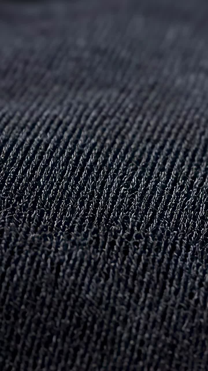Vertical video: Starting camera gliding over ribbed knit fabric in studio, revealing yarn fibers