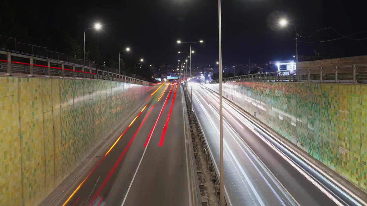 Tráfico en Msida, Malta, en Triq Mikiel Anton Vassalli a la salida de un túnel con estelas de luz y desenfoque de movimiento de coches en una concurrida vía arterial de noche en timelapse