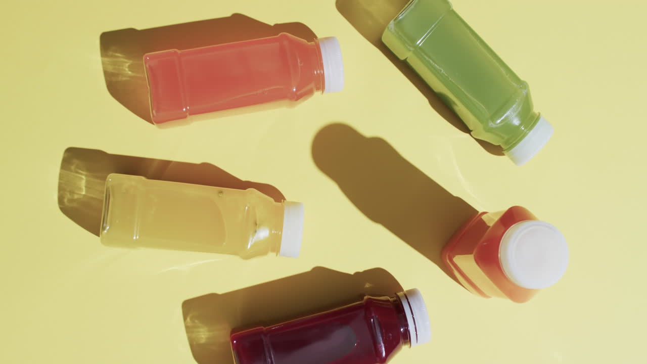 Video of bottles with fruit juices with copy space over yellow background