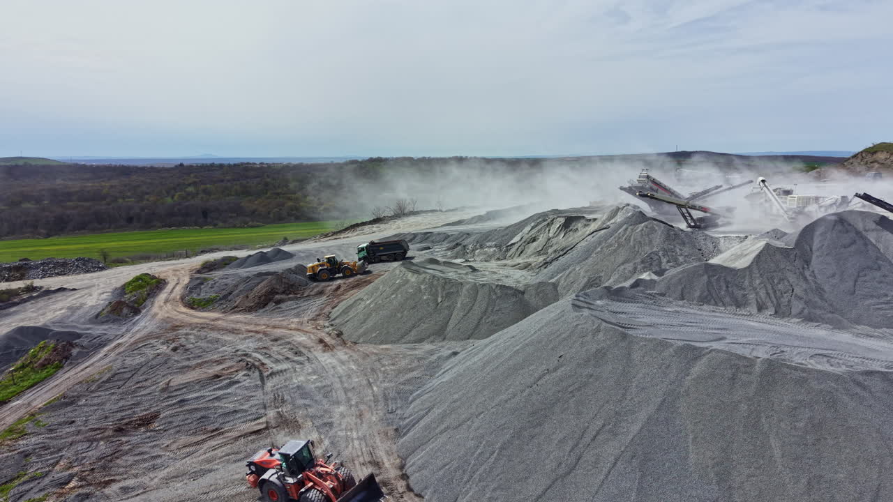 Granite quarry activity with machinery and piles of stone dust in a landscape during daylight hours, showing quarry operations and equipment