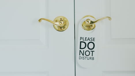 Honeymoon In A Luxury Hotel - Hand Hangs On Do Not Disturb Sign On A Wooden Door