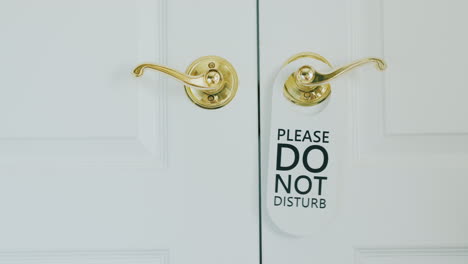 honeymoon in a luxury hotel - hand hangs on do not disturb sign on a wooden door