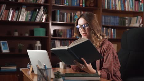 the woman is reading a book while talking to someone on a webcam, showing the book she is reading