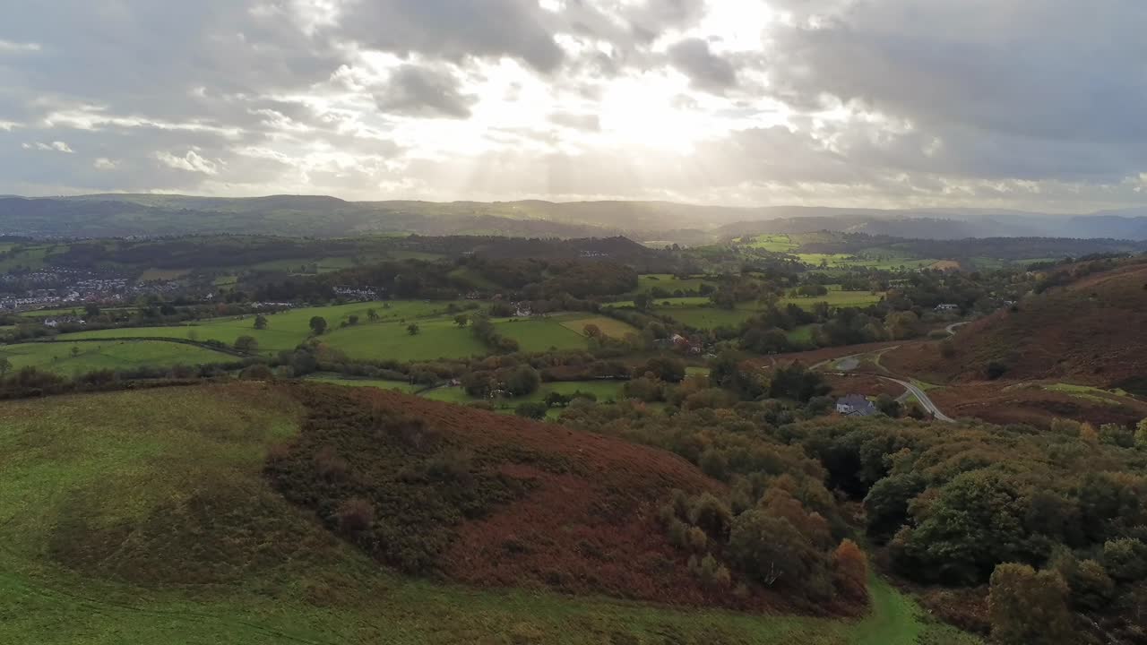 rayos de sol moviéndose a través de la campiña de mosaico rural pradera paisaje de tierras de cultivo vista de marcha atrás aérea