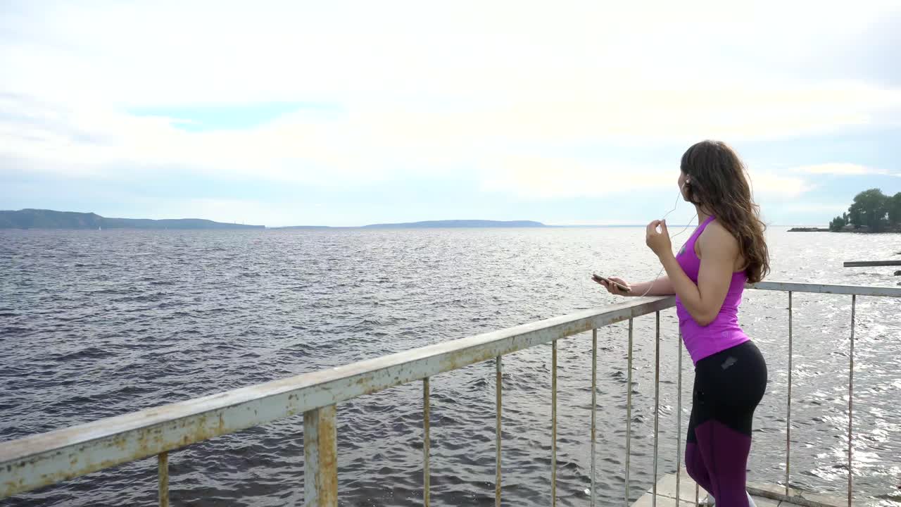 mujer disfrutando de la vista junto al río mientras escucha música