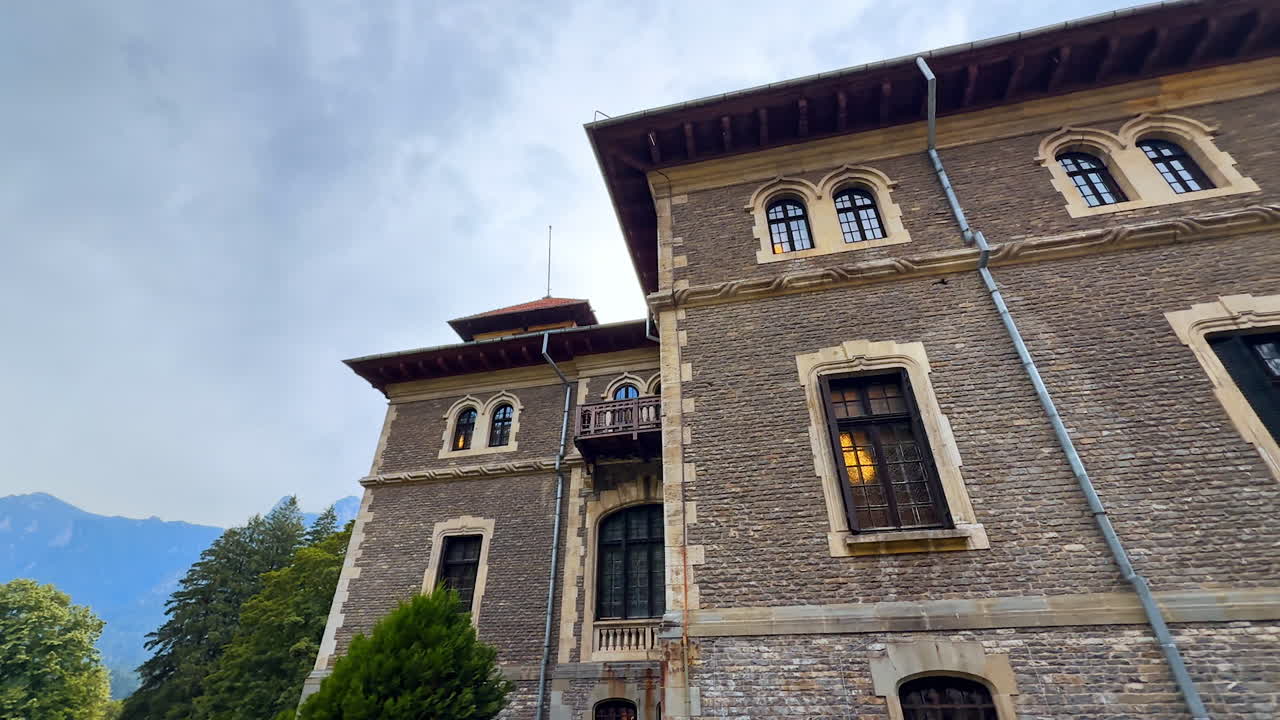Lamp switched on in the window of the old castle. Low angle view on the Cantacuzino Castle, Bu?teni, Romania on a rainy day