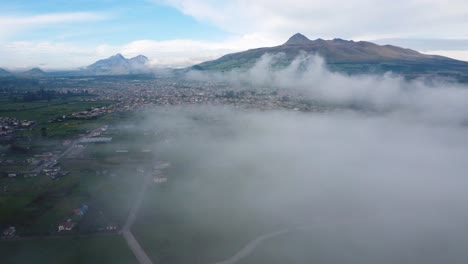 Impresionante-Clip-Aéreo-De-Drones-Sobre-Una-Pequeña-Ciudad-Y-Una-Gran-Zona-Montañosa-En-Neblina,-Machachi,-Corazon-Illinizas,-Ecuador