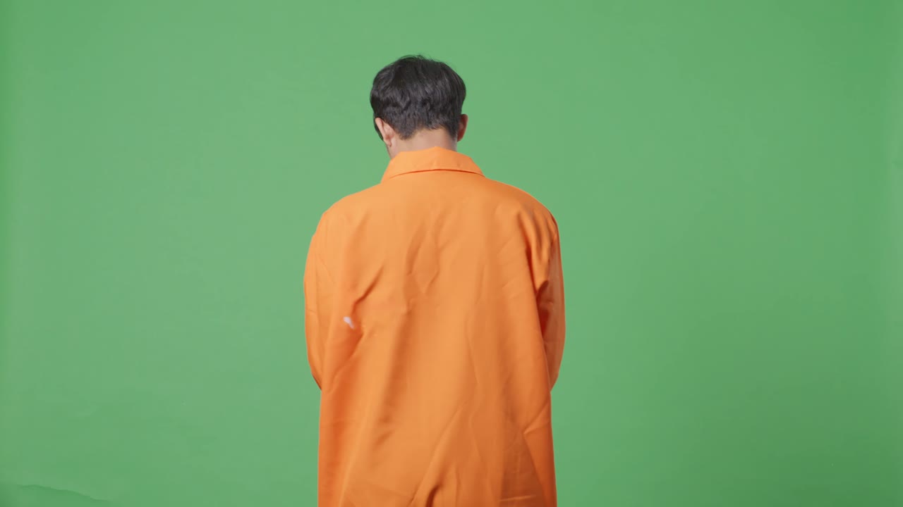 녹색 스크린 배경에서 손을 고 있는 아시아 남성 수감자의 뒷면