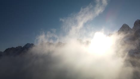 drone flight through clouds against sun and mountains , alps, vrsic pass, slovenia