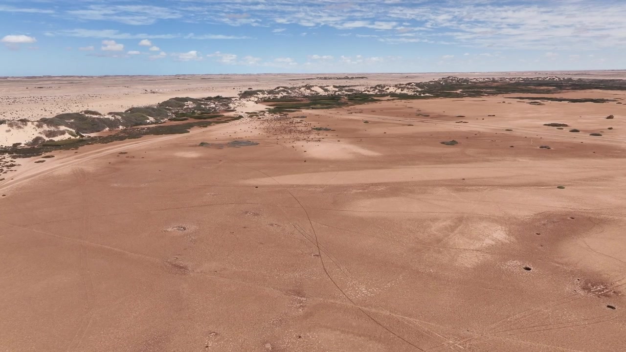Dronekuva Dakhlan lähellä sijaitsevasta rannikon autiomaasta, esitellen laajoja kuivia tasankoja, hajallaan olevaa kasvillisuutta ja Marokon Atlantin Saharan koskemattomia luonnonmaisemia