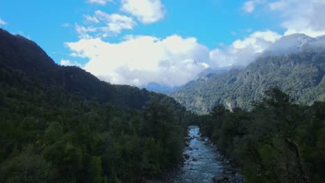 Dolly-out-aerial-view-of-the-Rio-Blanco-and-the-forest-of-Hornopiren-National-Park-with-snow-capped-mountains-in-the-background,-Hualaihue,-Chile