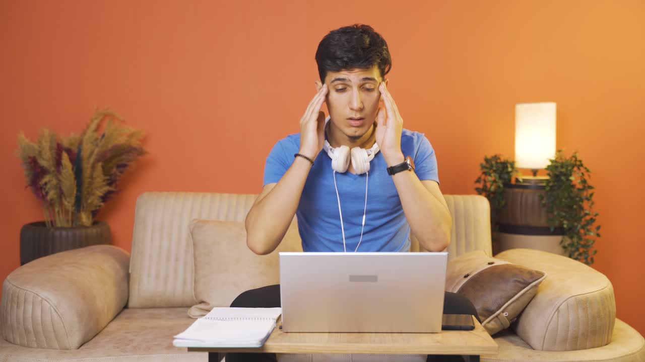 Man working on laptop has a headache.