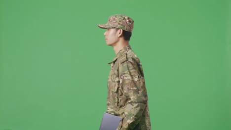 side view of asian man soldier holding a tablet while walking in the green screen background studio