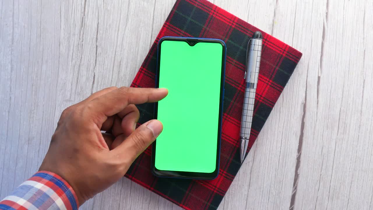 Vista superior de la mano del hombre con un teléfono inteligente en el escritorio de la oficina