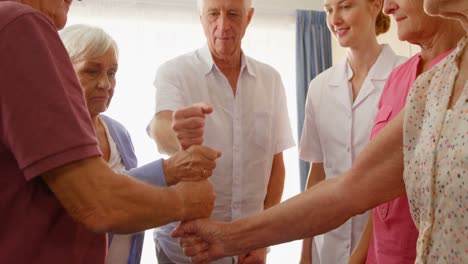 grupo de personas mayores y terapeuta poniendo su puño juntos