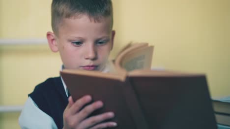 escolar en chaleco hace la tarea con el libro en la habitación en casa