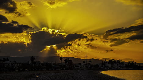 Toma-De-Timelapse-De-La-Orilla-Del-Mar-Con-El-Sol-Poniéndose-A-Través-De-Las-Nubes-Durante-La-Noche