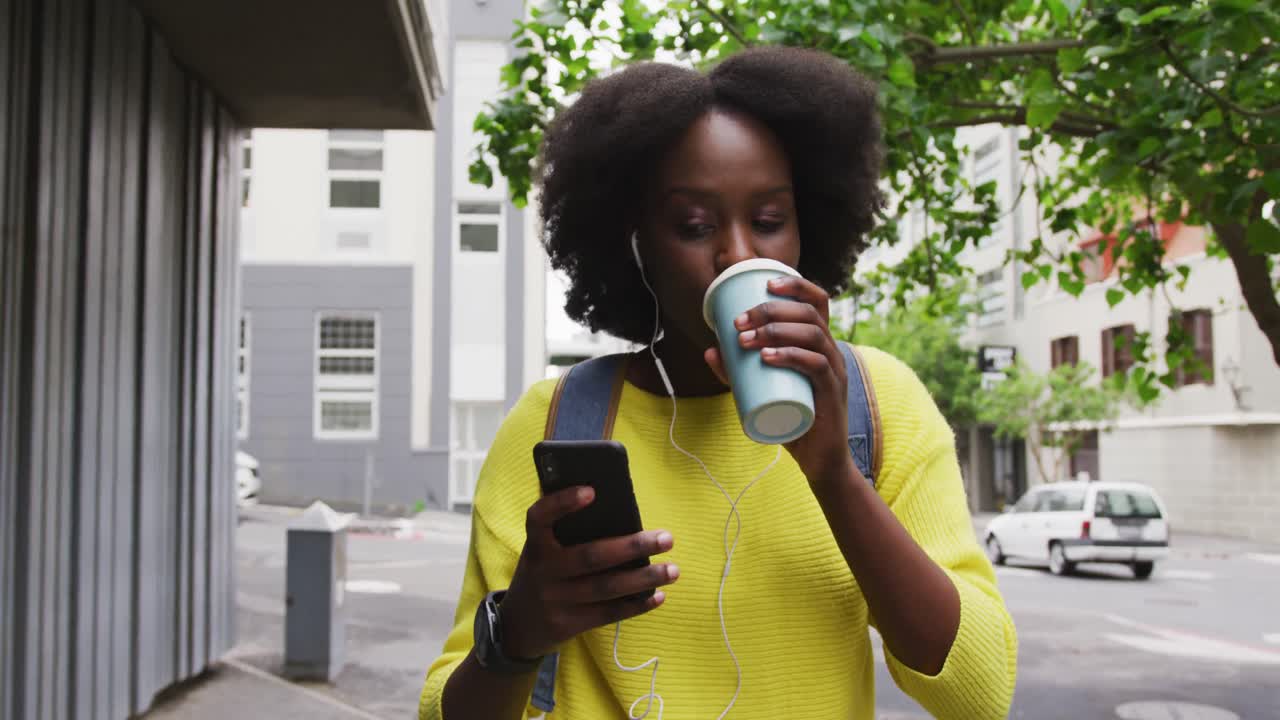mujer afroamericana usando un teléfono inteligente en la calle