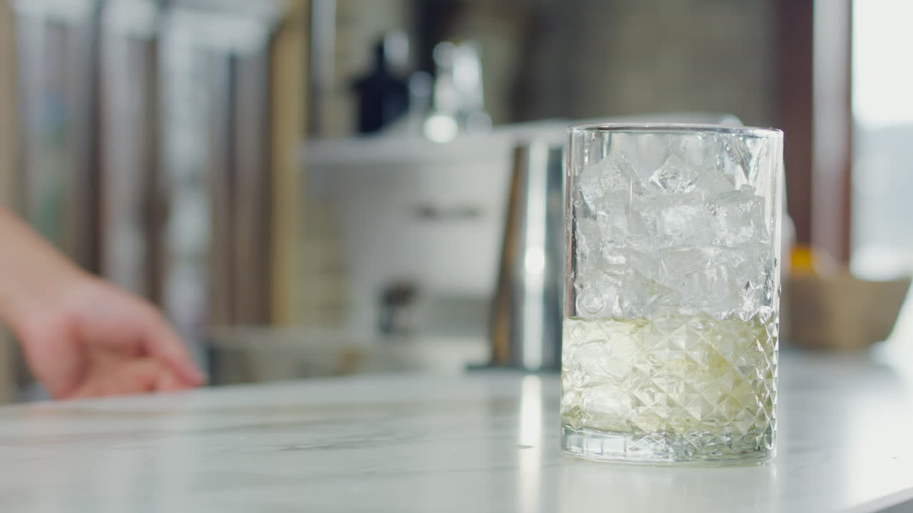 Bartender mixing a drink with ice in a glass, showing the process in close-up