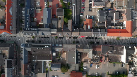 Aerial-birds-eye-panning-view-of-city-street-neighborhood-in-Ebjerg,-Denmark.-Overhead-slow-fly-by-view-pedestrian-strolling-down-the-road-and-car-parked-in-parking-lot