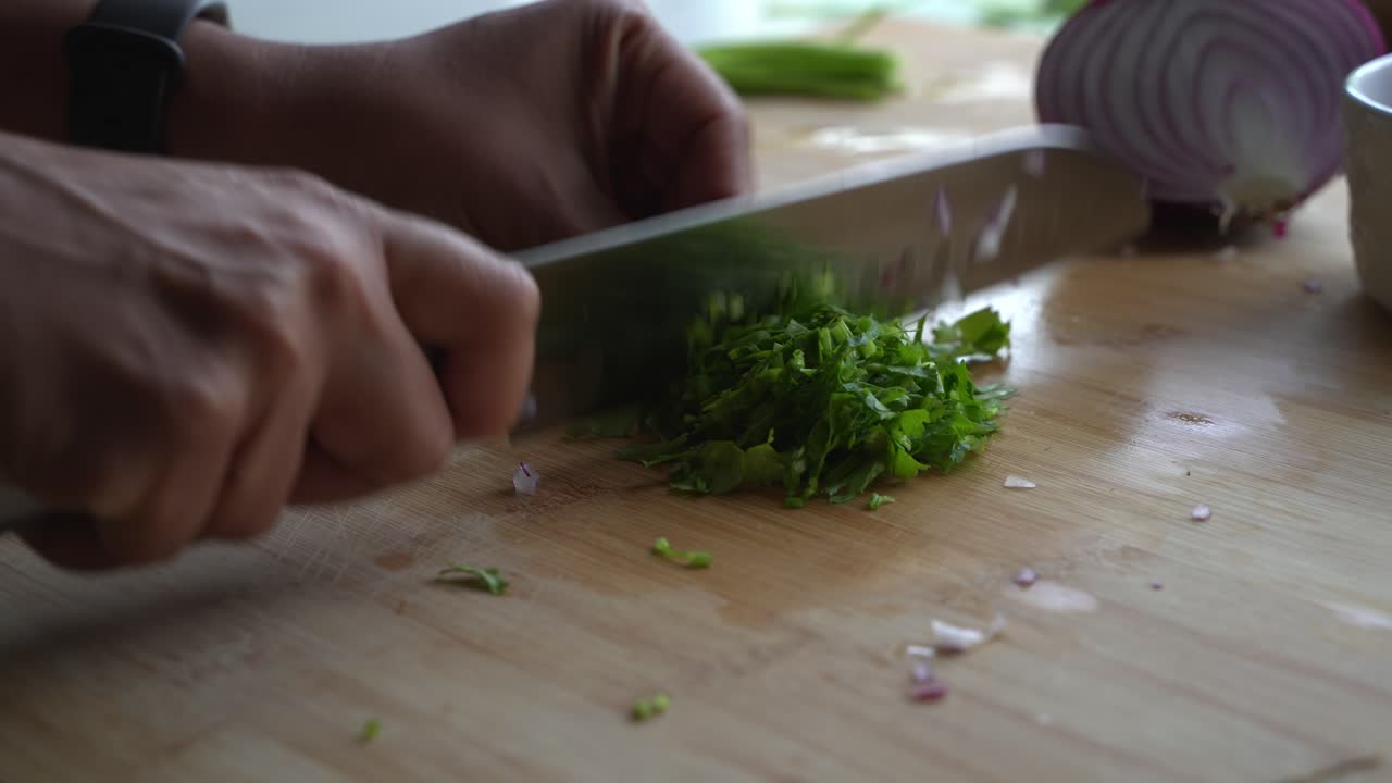 Chopping cilantro leaves into small pieces for garnish and flavor special ingredients to cook a meal two cans of beans rice plantain avocado red