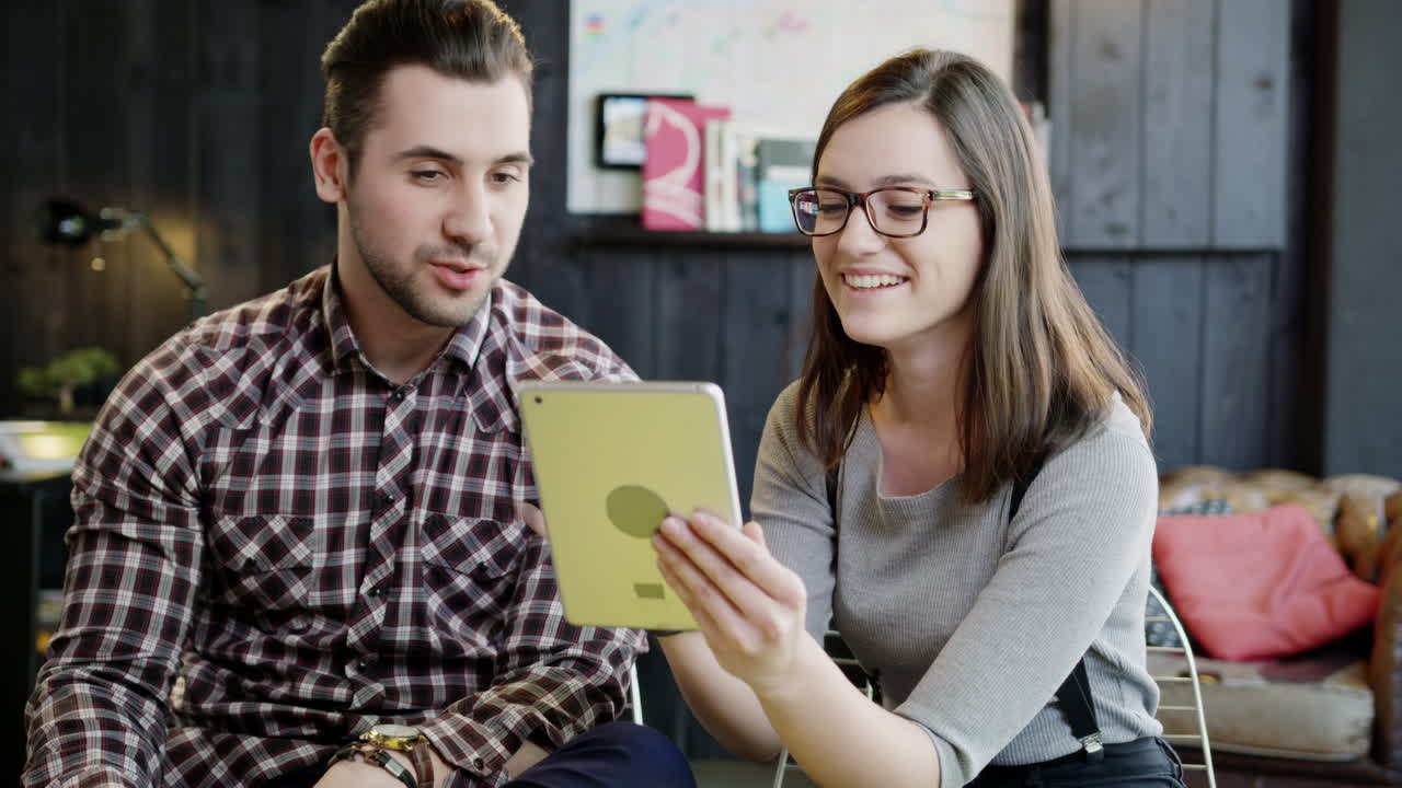 una pareja joven revisando la tableta juntos.