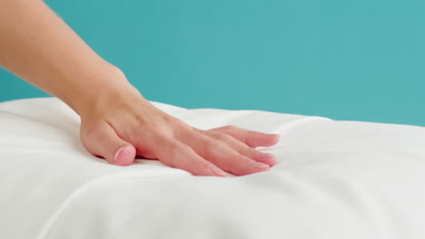 la mano de una mujer tocando una almohada blanca