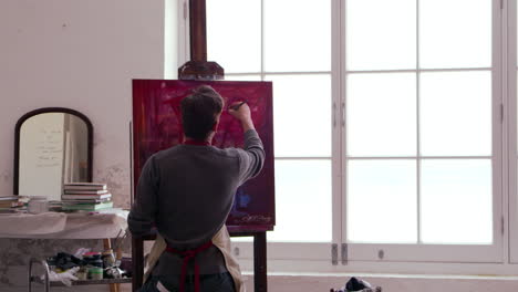 male artist works on painting in daylight studio shot on r3d