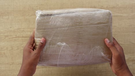 hands holding a wrapped cardboard box