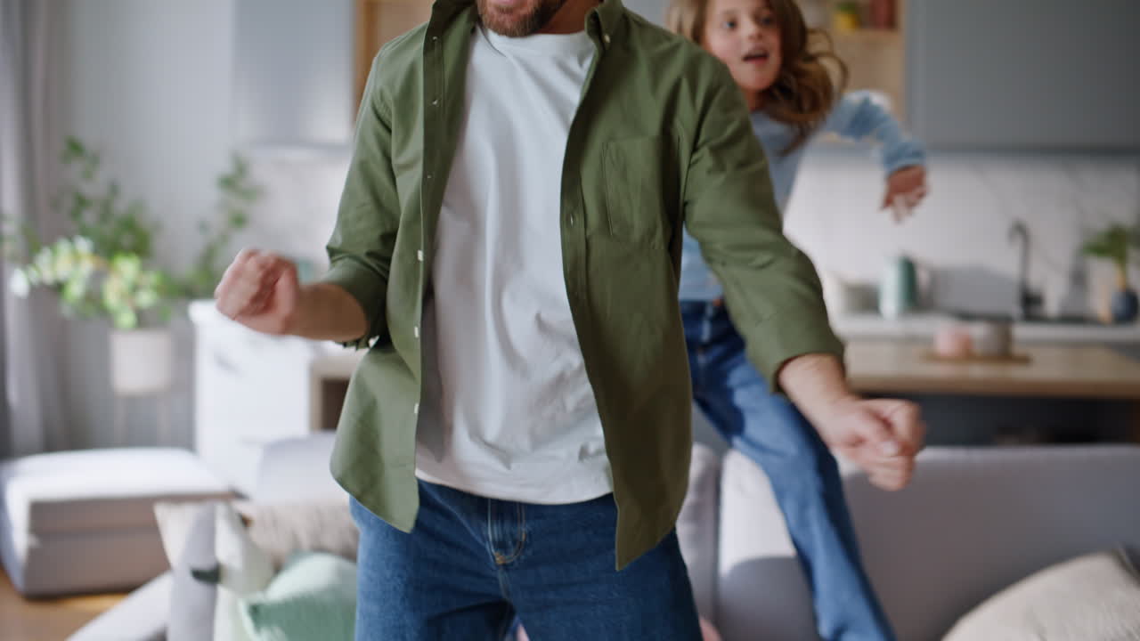 Playful girl dancing daddy in living room closeup. Carefree little daughter
